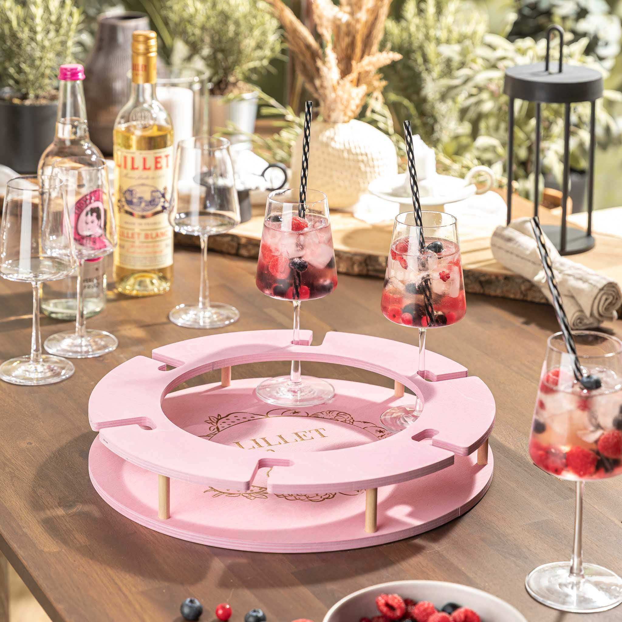AperitifBar Berry in zartem Rosa mit Lillet-Gläsern und Beeren, dekorativ auf einem Tisch im Garten platziert.