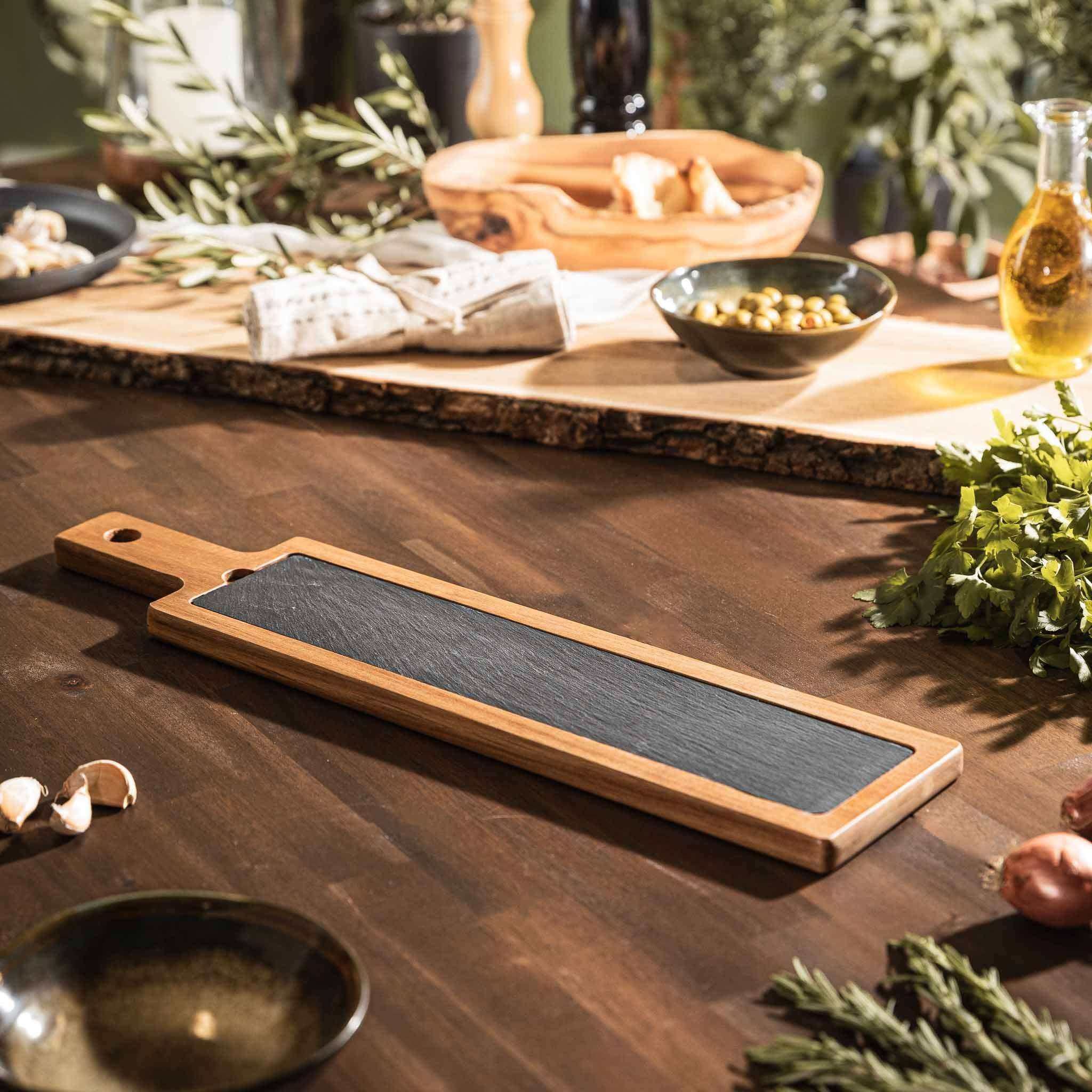 Gourmet Board aus Akazienholz und Schiefer auf einem Tisch, perfekt für Käse und Tapas.