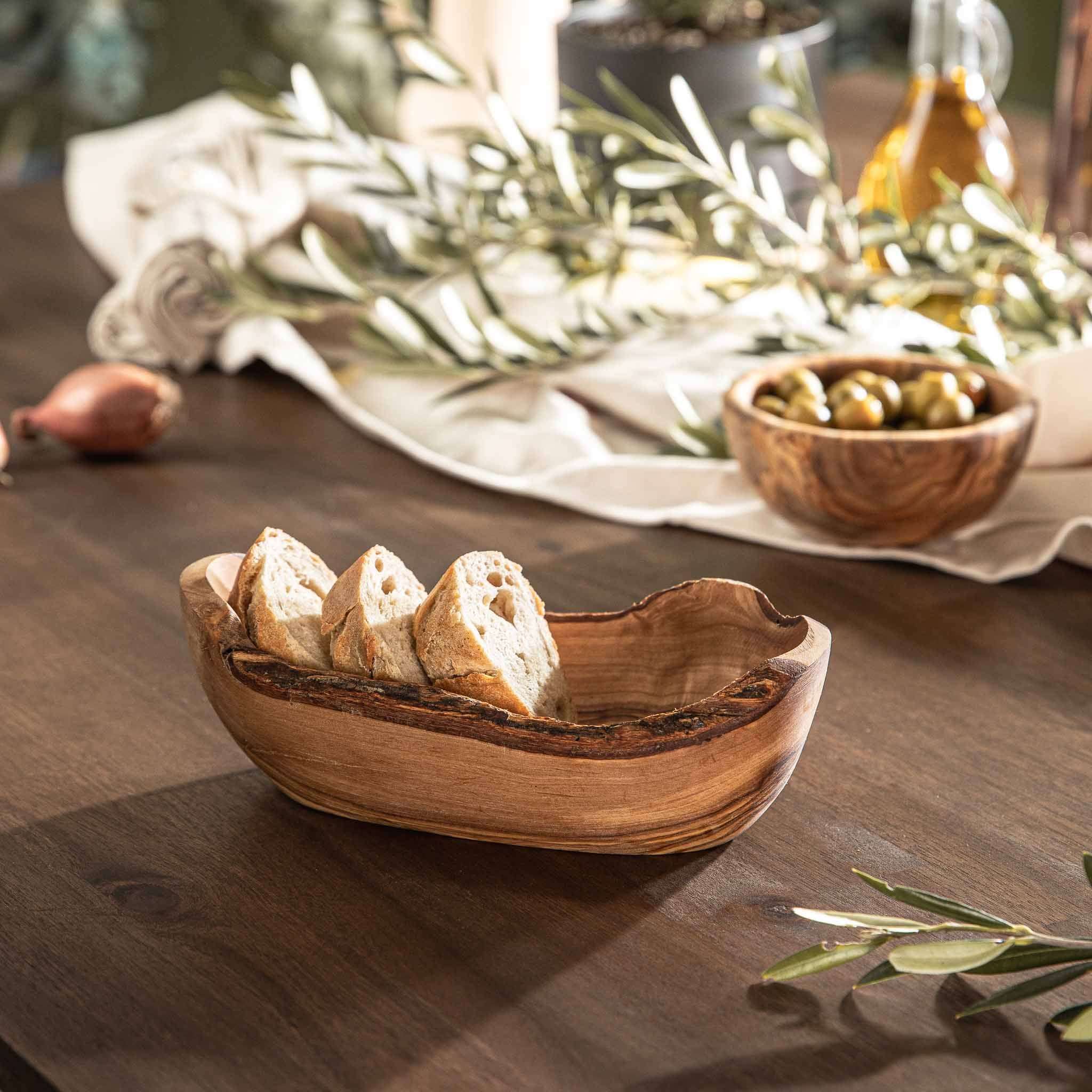 Olive Bowl Slim aus rustikalem Olivenholz mit natürlicher Rinde, gefüllt mit Brot auf einem Tisch.