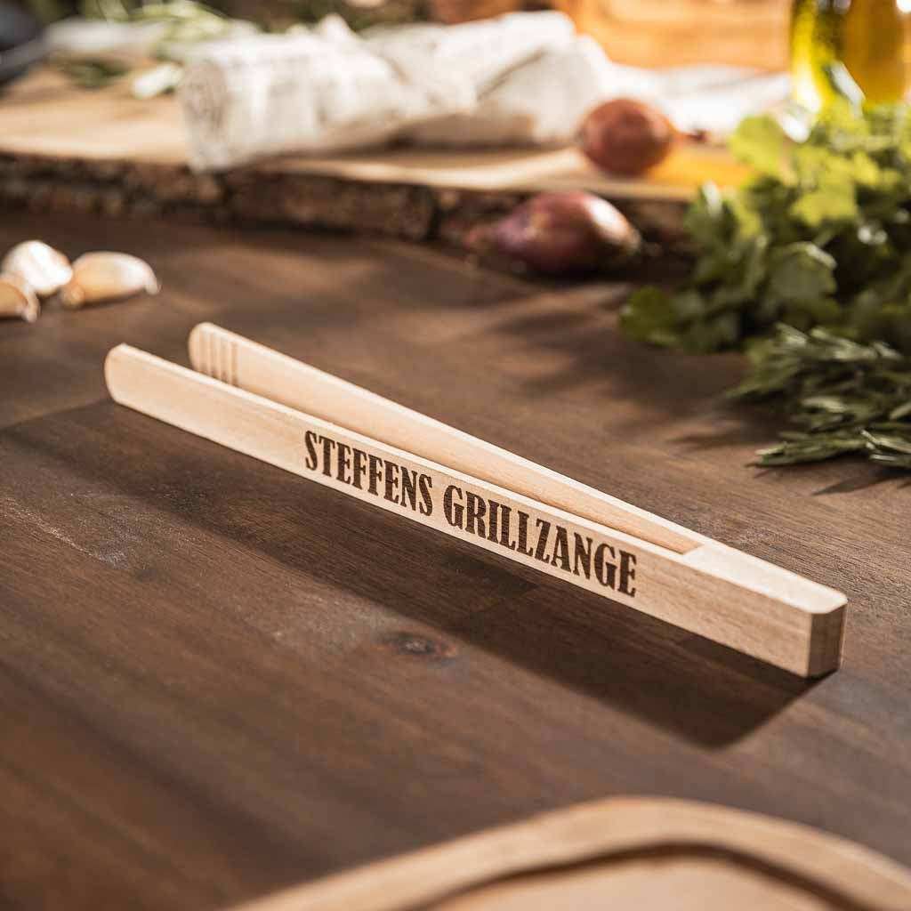 Personalisierbare Servierzange aus Buchenholz auf Holztisch.