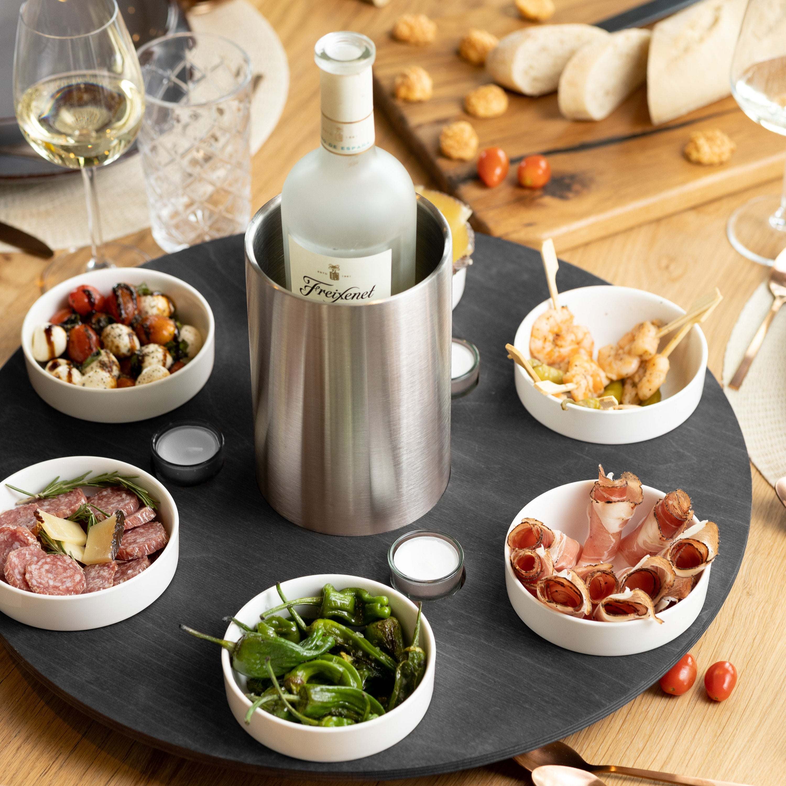 Robust Drehteller with snacks, wine cooler, and tealight holders on a wooden table.