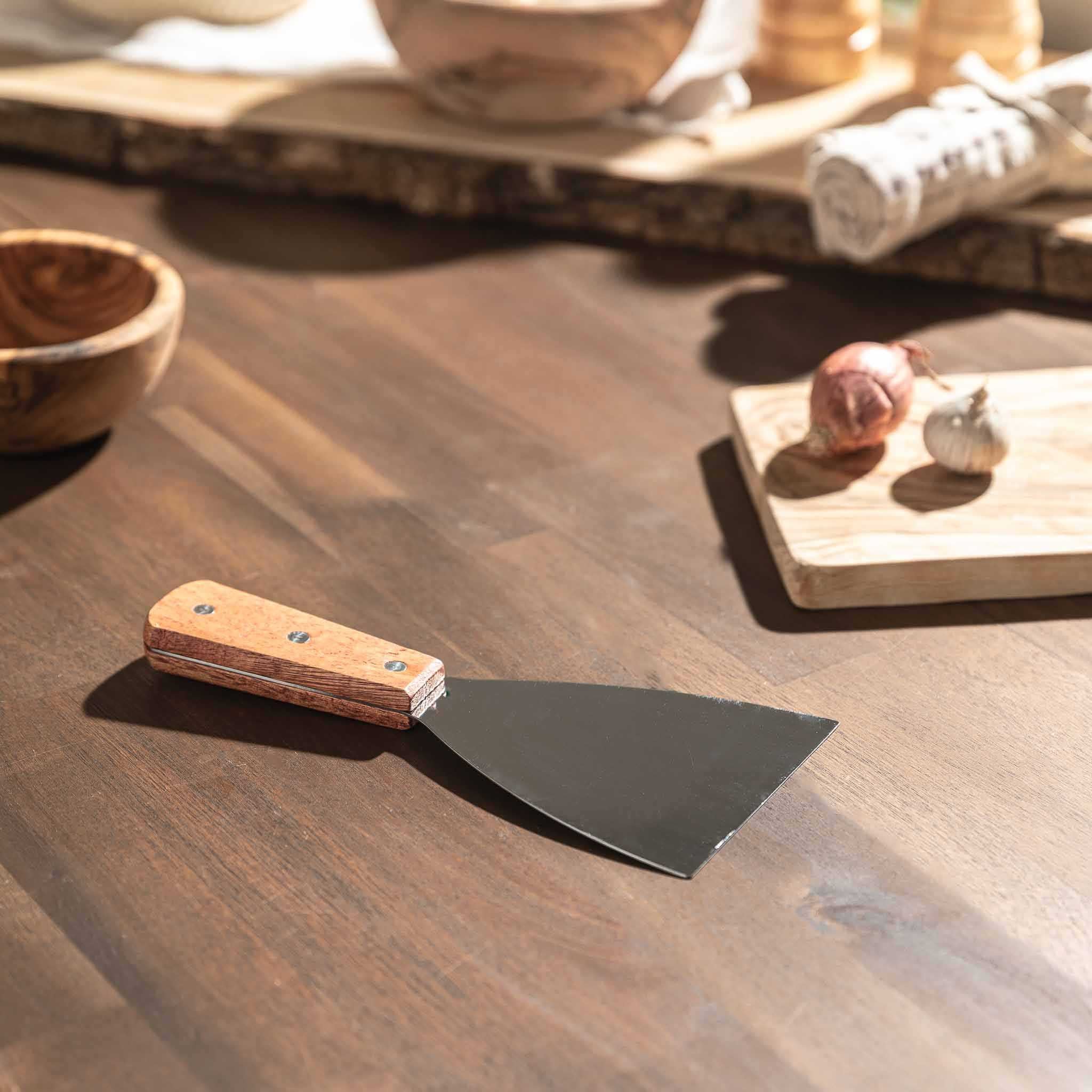 Pfannenwender mit robustem Holzgriff und Edelstahlfläche auf einem Holztisch, ideal für Grill und Pfanne.
