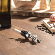 Ausgießer on wooden table with bottle, featuring sleek stainless steel design for precise pouring.