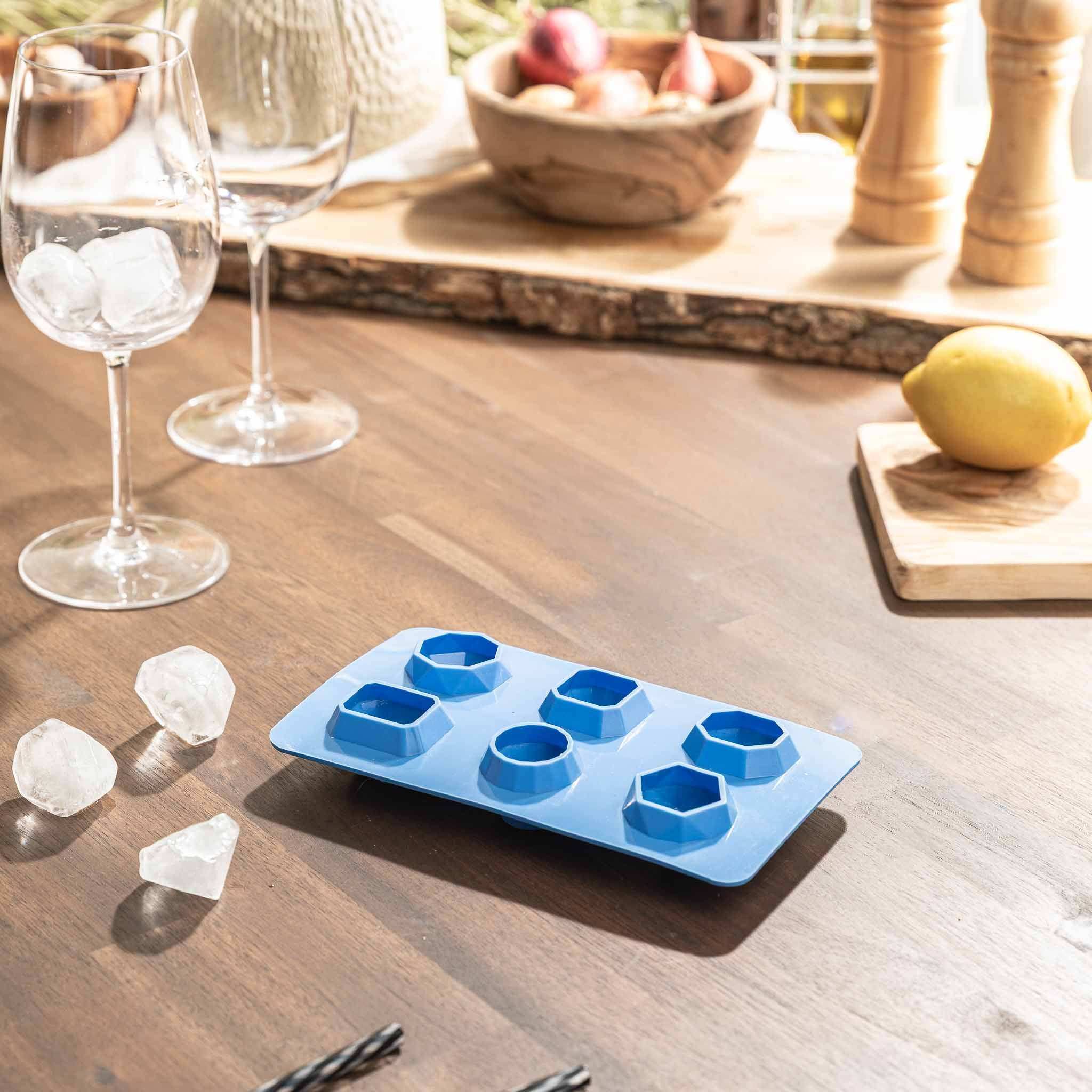 Silikon Eiswürfelformen auf einem Tisch mit Gläsern und Eiswürfeln.