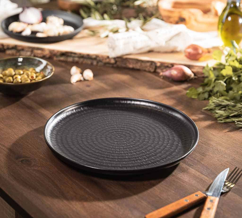Schwarzer Porzellanteller von HOTTY Porzellan-Geschirr auf Holz-Tisch, edles Design, ideal für stilvolles Dining.